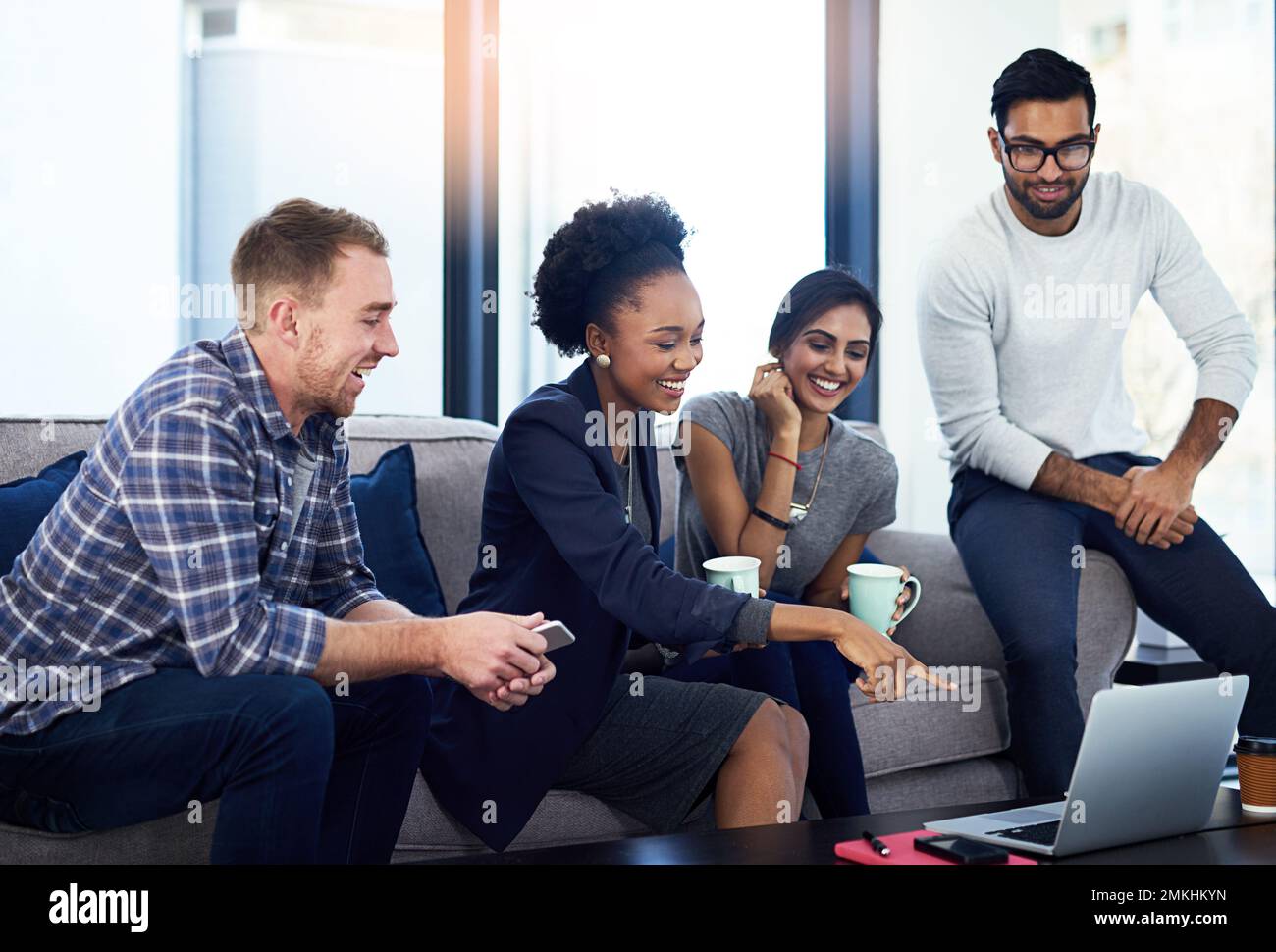 Il divertimento fa parte della loro cultura aziendale. un gruppo di colleghi che si riunisce in modo informale su un divano al lavoro. Foto Stock