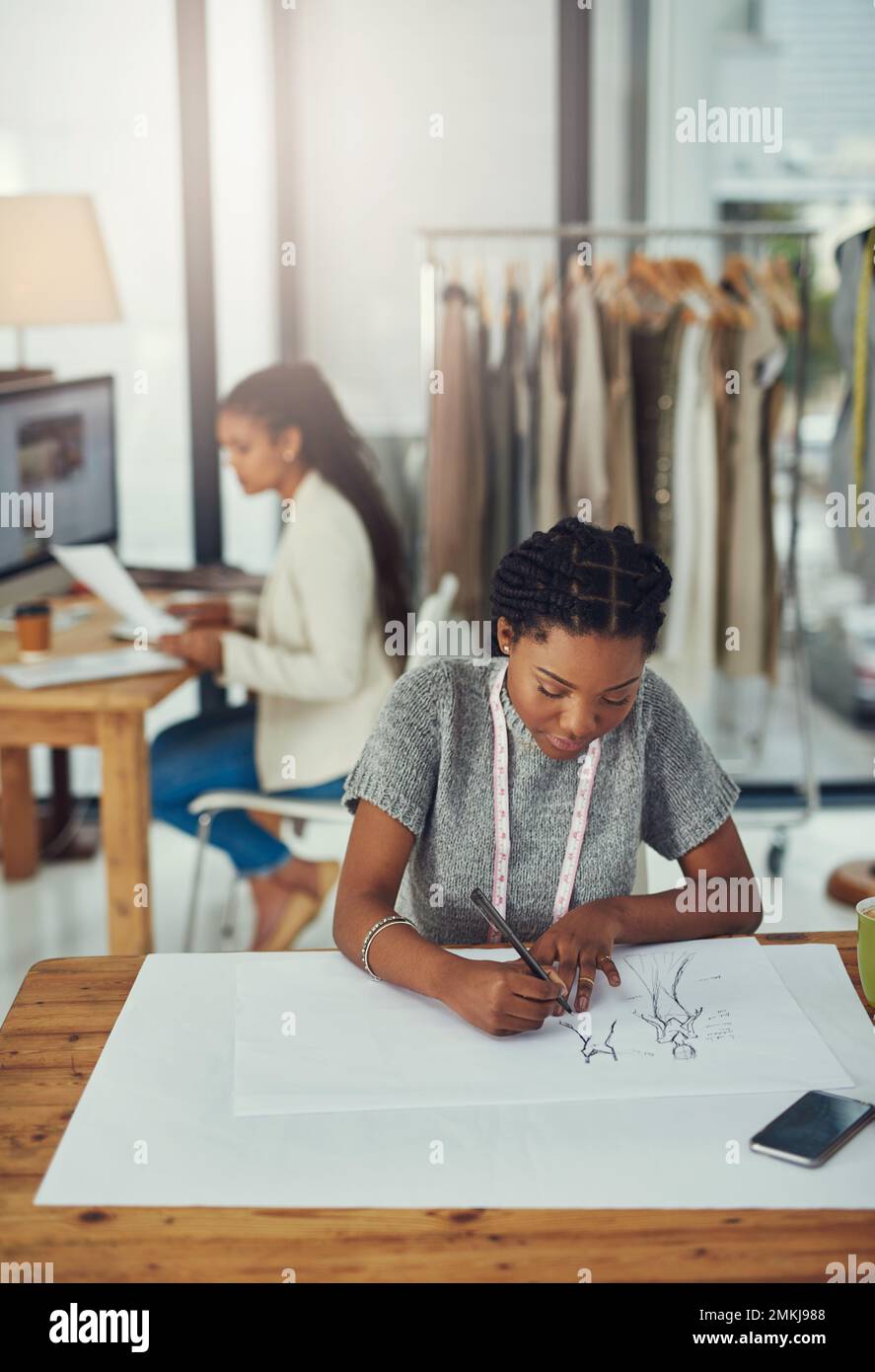 Cambiare il mondo un progetto alla volta. un designer di moda che lavora alla sua ultima creazione con la sua collega sfocato. Foto Stock
