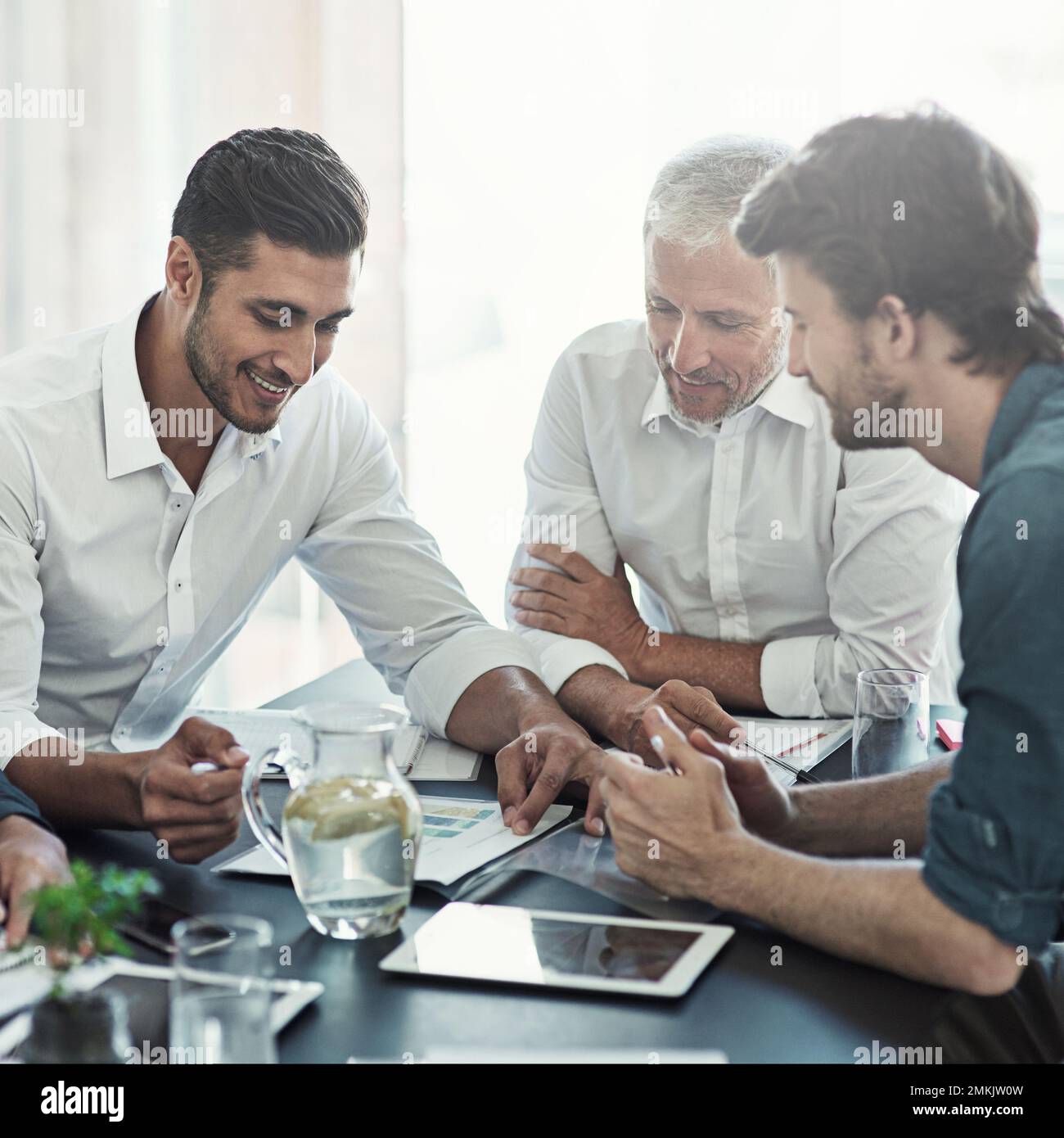 Un gruppo di uomini d'affari che si riunisce intorno a un tavolo in un ufficio. Foto Stock