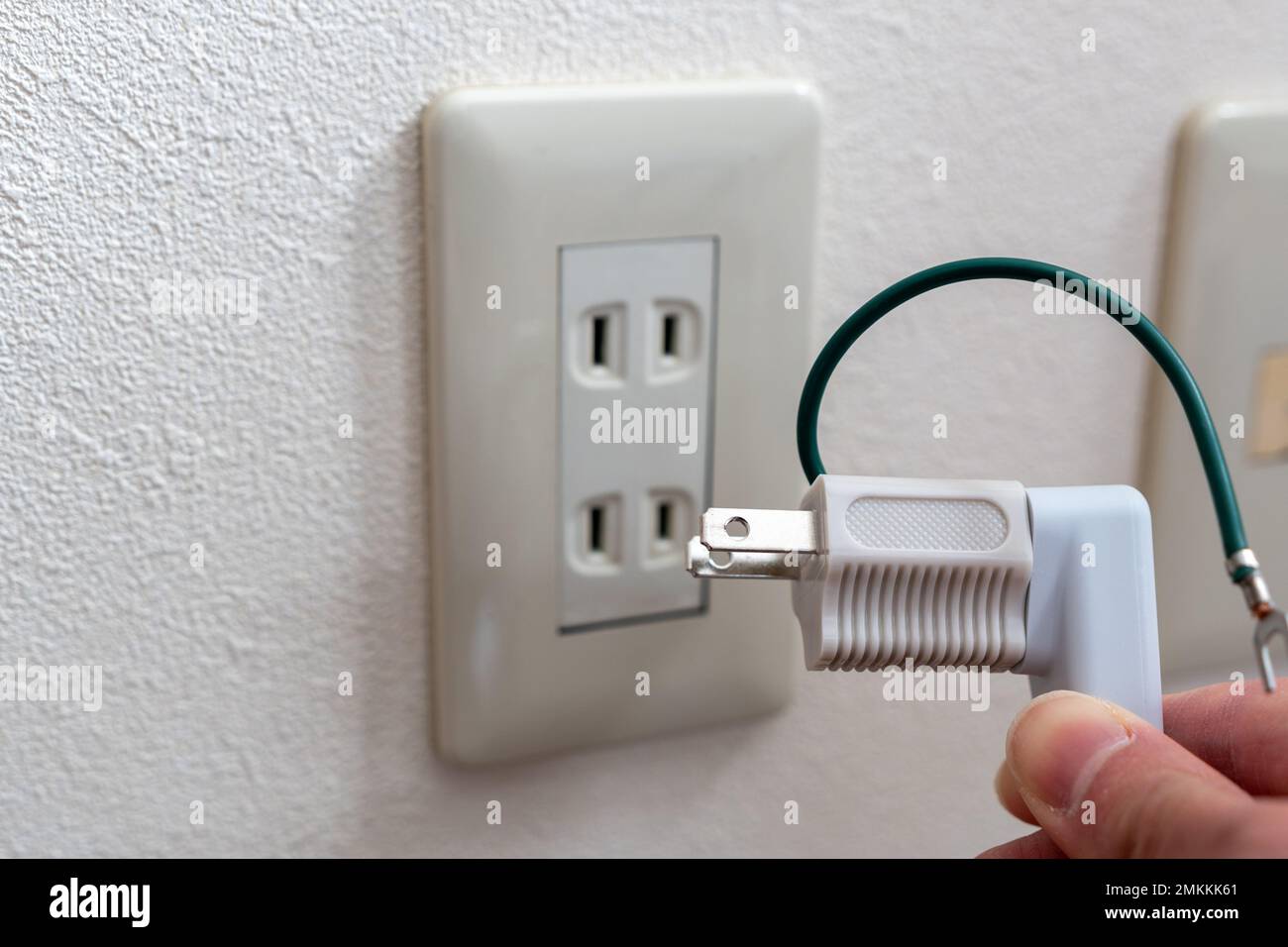 Una presa a muro giapponese senza morsetto di messa a terra. spina di alimentazione a 3 pin collegata a un adattatore da viaggio. Foto Stock