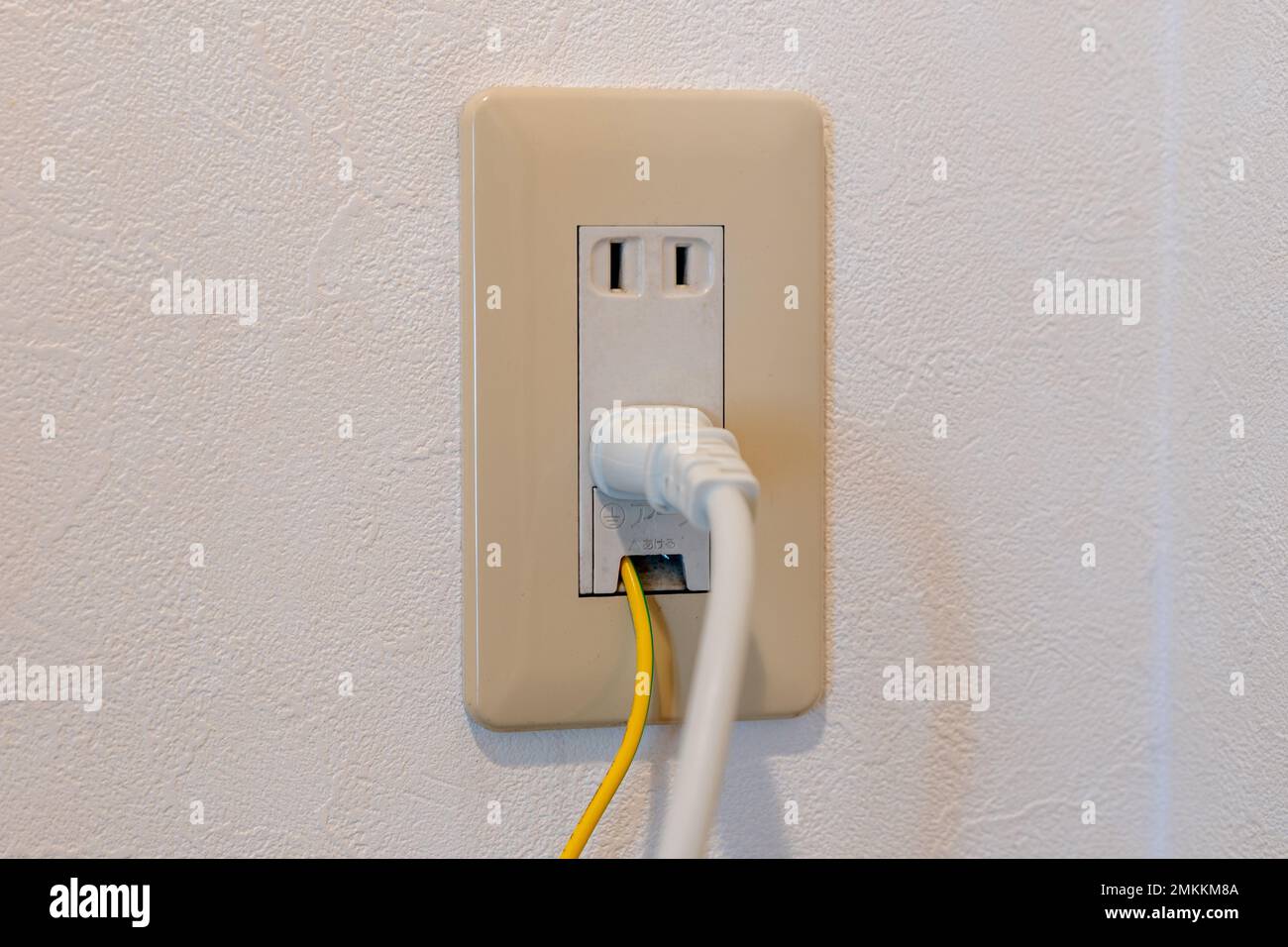 Spina di alimentazione e cavo di messa a terra collegati alla presa elettrica giapponese a muro. Traduzione in giapponese "interruzione nel filo di massa". Foto Stock