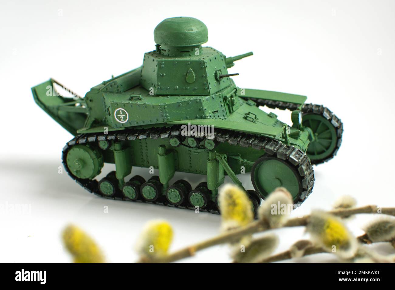 Modello di un vecchio carro armato sovietico fatto di carta su sfondo bianco. Willow ramo in primo piano. Primo piano. Il concetto di fatto a mano. Foto Stock
