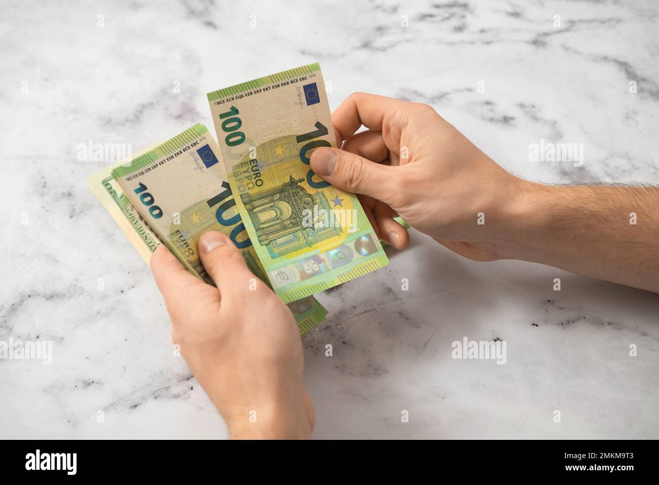 Un uomo conta il denaro in euro con le mani su uno sfondo chiaro, il concetto di economia, la distribuzione del denaro Foto Stock