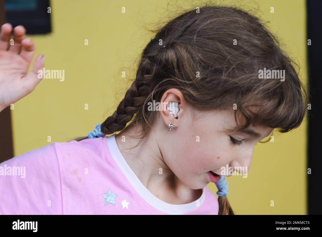 Ragazza con un caldo bastoncino di cotone terapeutico nell'orecchio con un viso triste e terzoso sta tenendo l'orecchio. Dolore all'orecchio, otite media, gonfiore della guancia, gengive Foto Stock