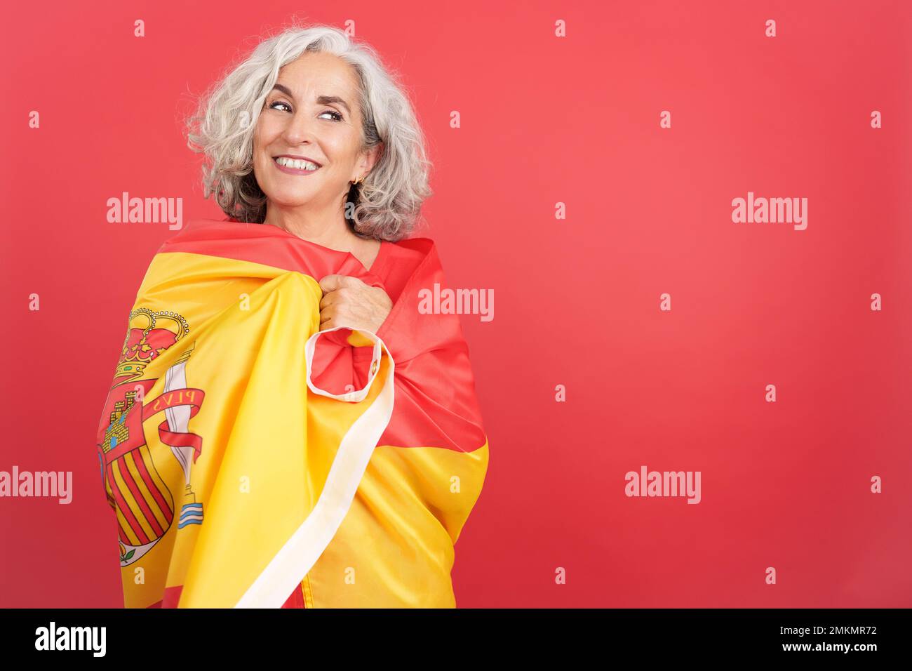 Donna felice che si avvolge con una bandiera nazionale spagnola Foto Stock
