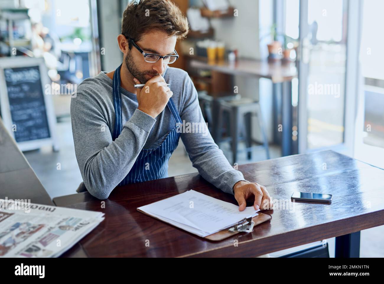 Il lavoro duro è un buon giovane proprietario di una caffetteria che fa un po' di documenti. Foto Stock