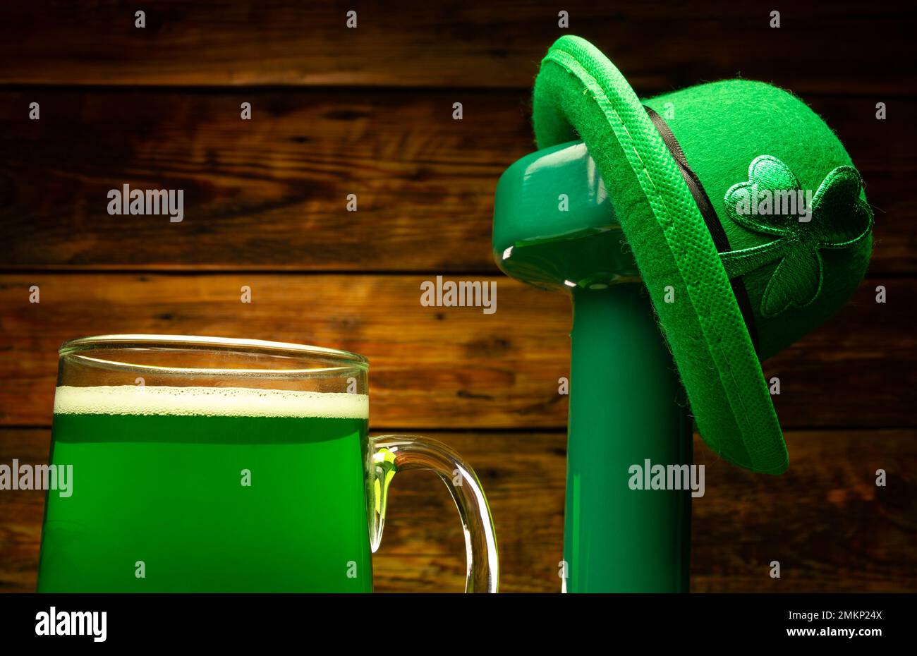 Manubri da palestra, bicchiere di birra verde, cappello irlandese con mantello di foglie di shamrock. Composizione sana di allenamento fitness per St. Giorno di Patrick. Foto Stock