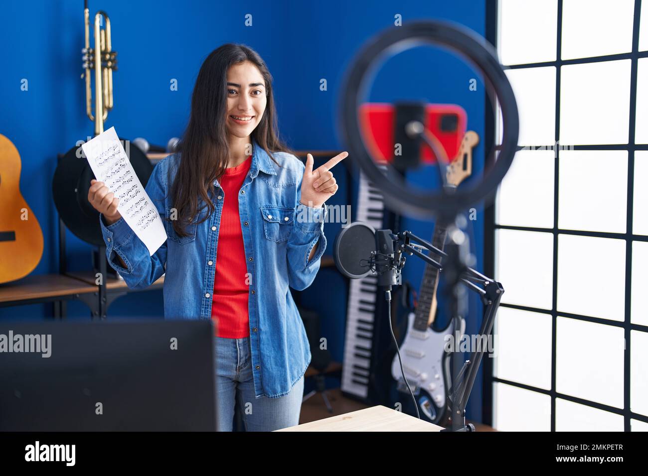 Ragazza giovane adolescente che fa online tutorial di musica mostra  spartiti sorridente felice indicando con mano e dito a lato Foto stock -  Alamy