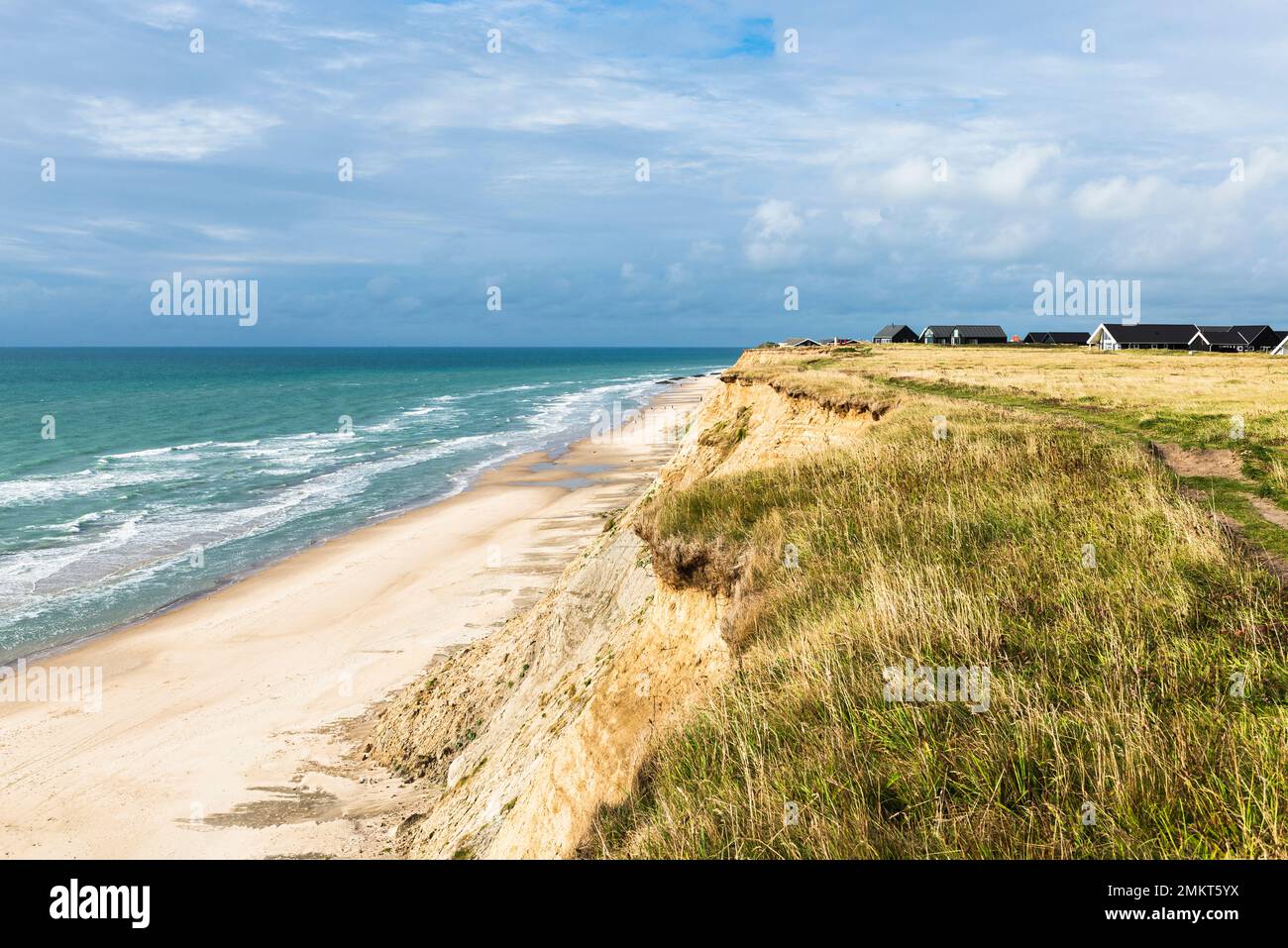 Danimarca, Nord Jutland, Lönstrup: Case vacanze nelle dune sopra le scogliere e il mare della baia di Jammer in sole con cielo nuvoloso Foto Stock