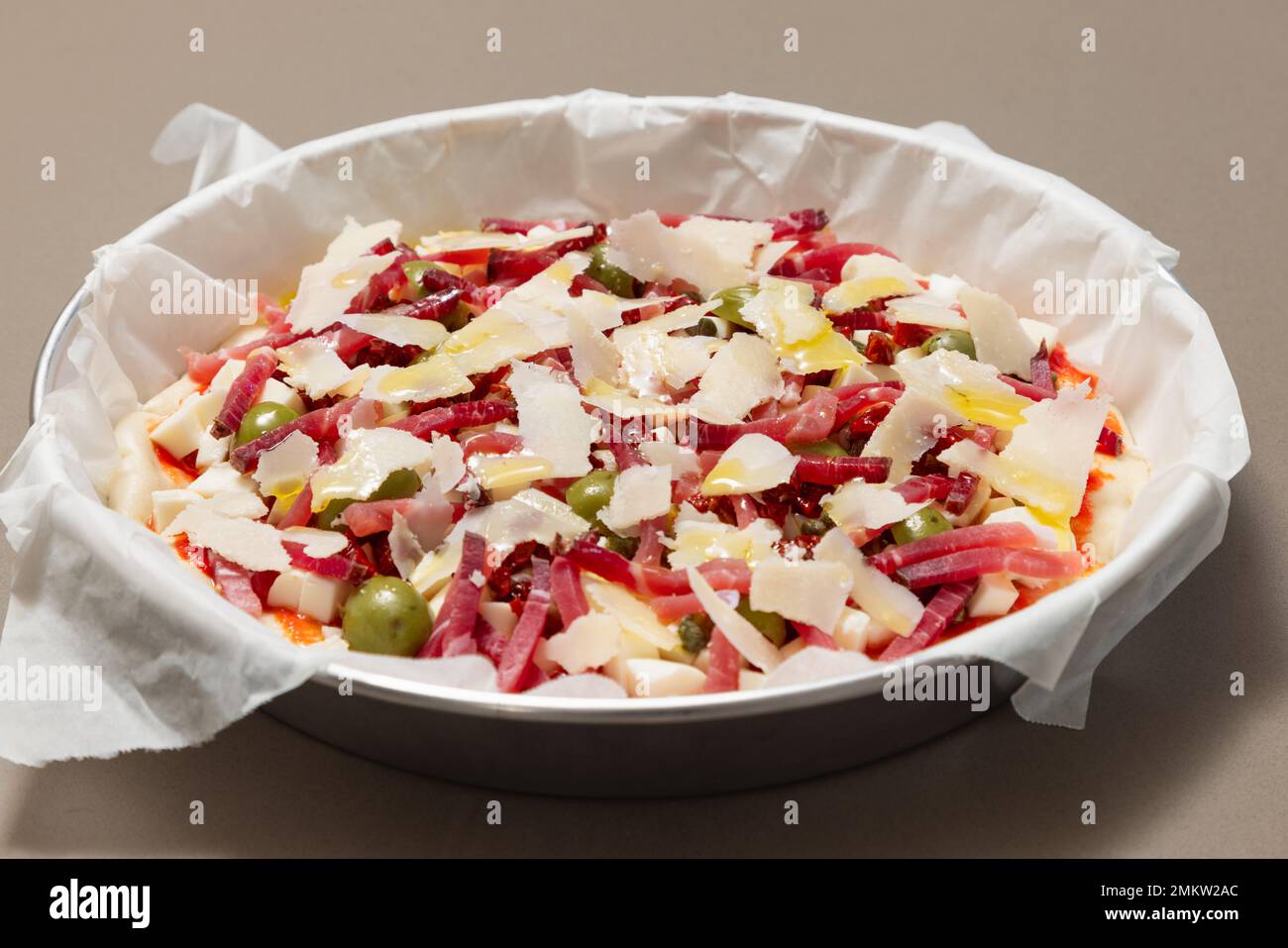 Pizza italiana fresca fatta in casa con pancetta, olive, capperi e parmigiano pronti per la cottura Foto Stock