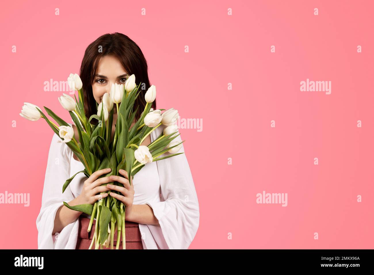 Felice giovane donna caucasica in casual godere aroma bouquet di fiori, compleanno e tempo libero Foto Stock