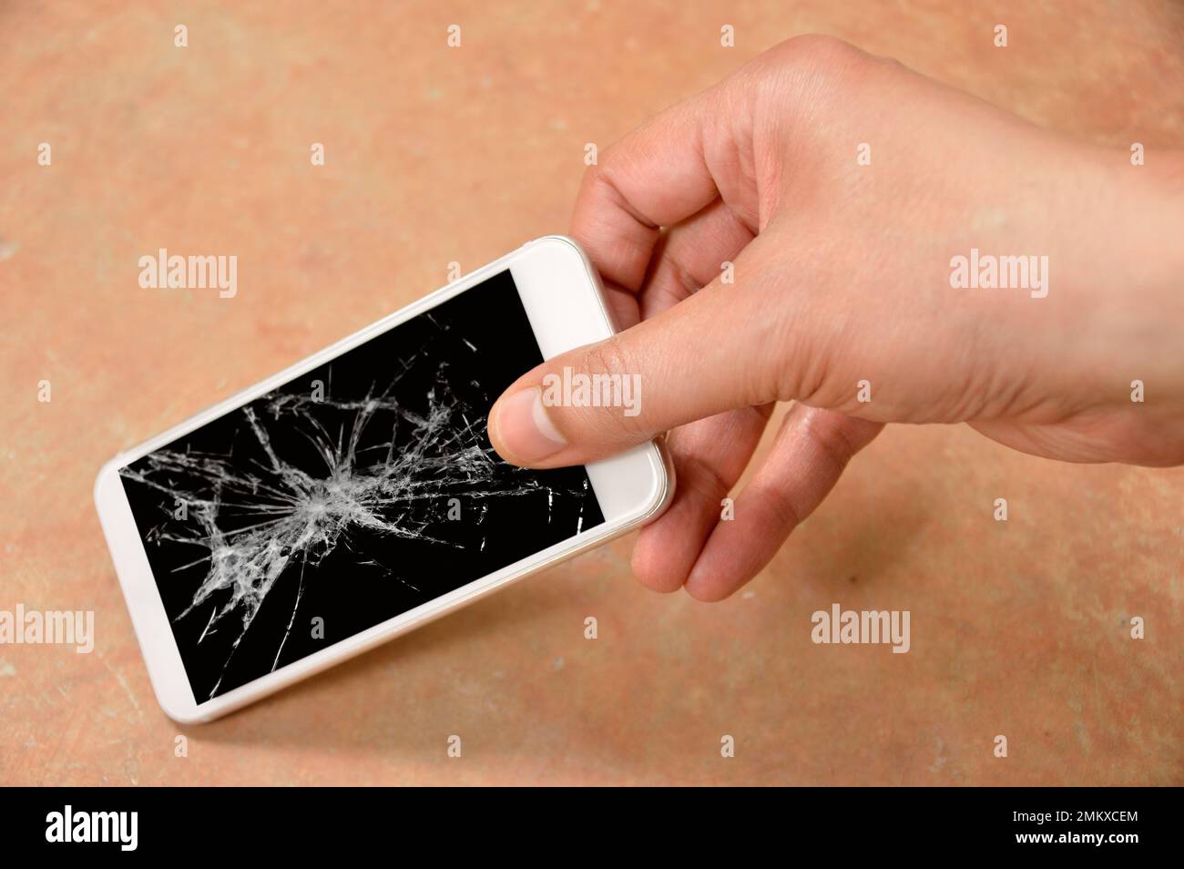 Persona che picking smartphone rotto con schermo rotto sul pavimento a casa Foto Stock
