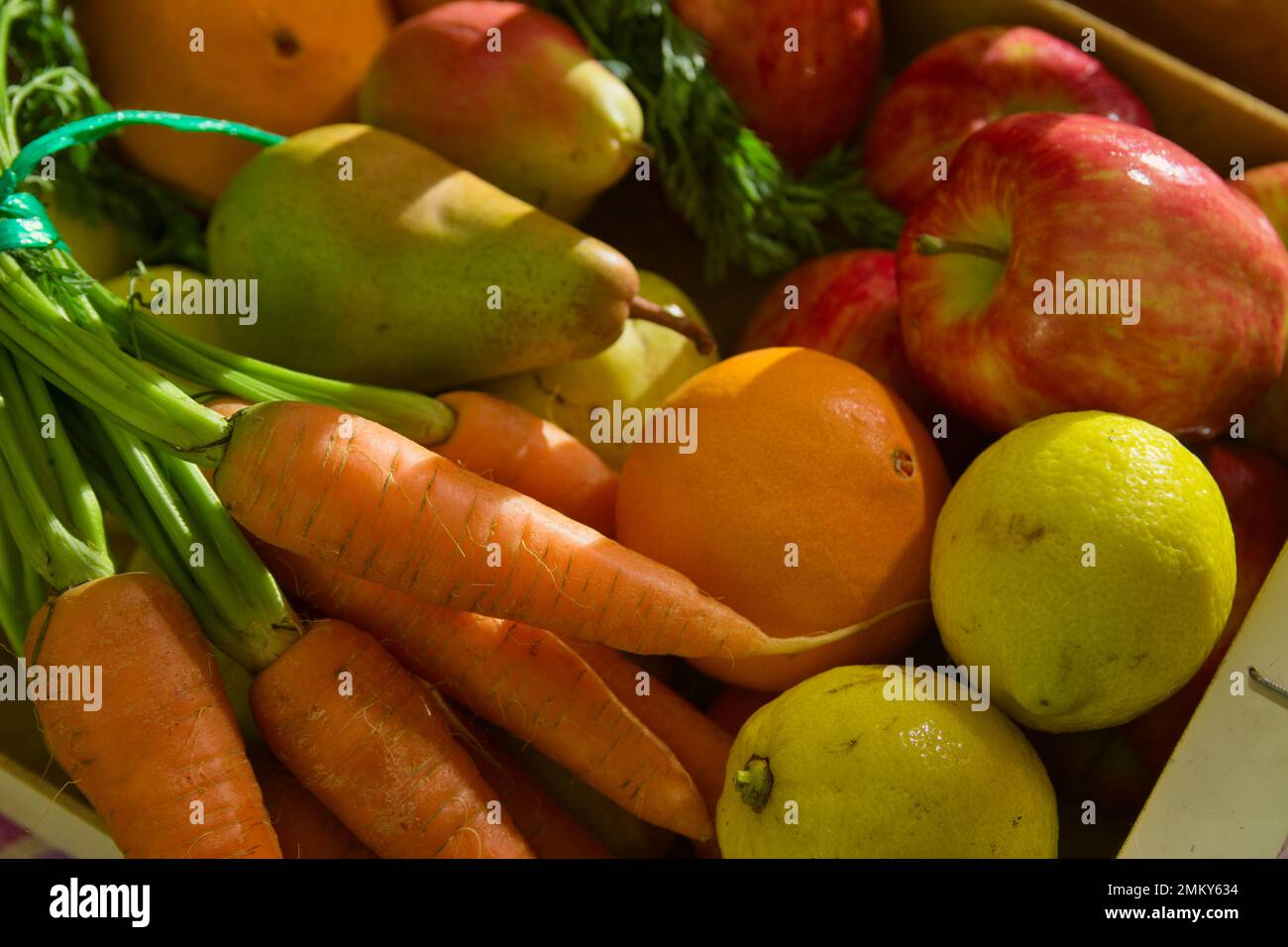 Primo piano di un mazzo di frutta e verdura assortite con banane, mele, limoni, pere e carote alla luce del tardo pomeriggio Foto Stock