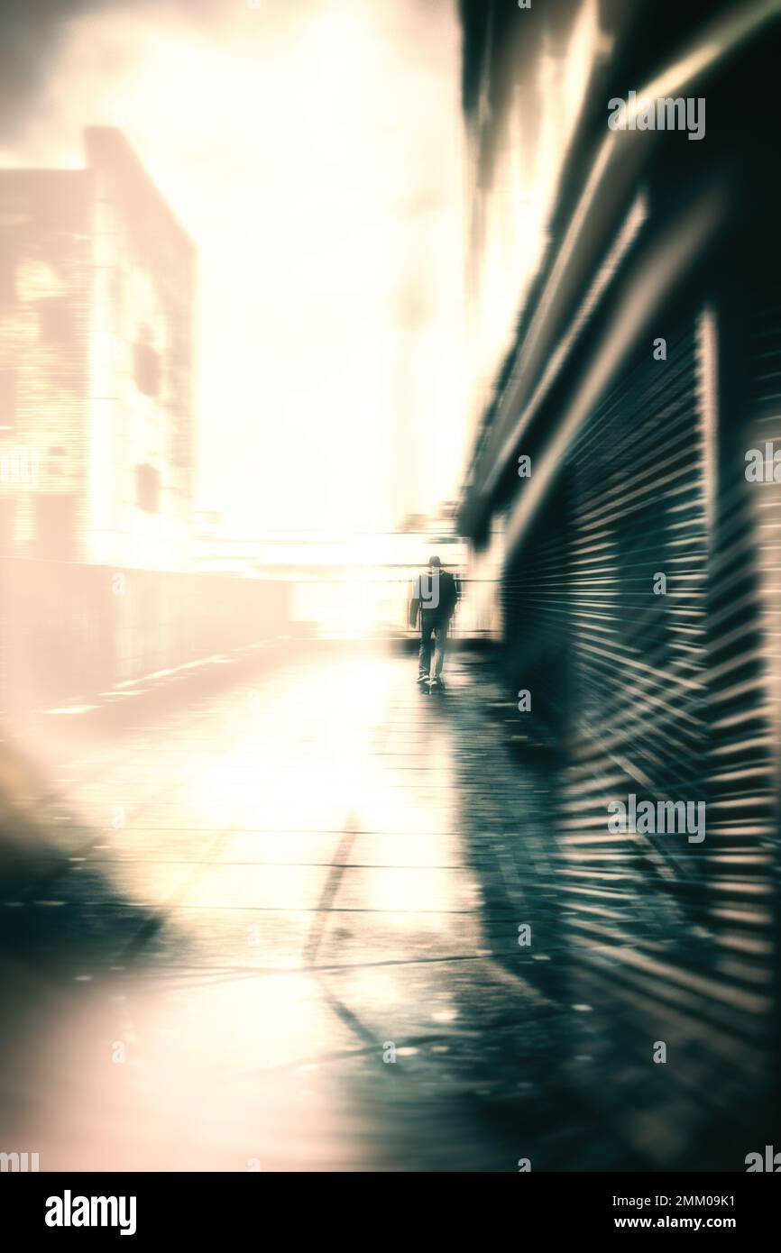 Silhouette sfocata su un uomo che cammina accanto a edifici derelitti Foto Stock