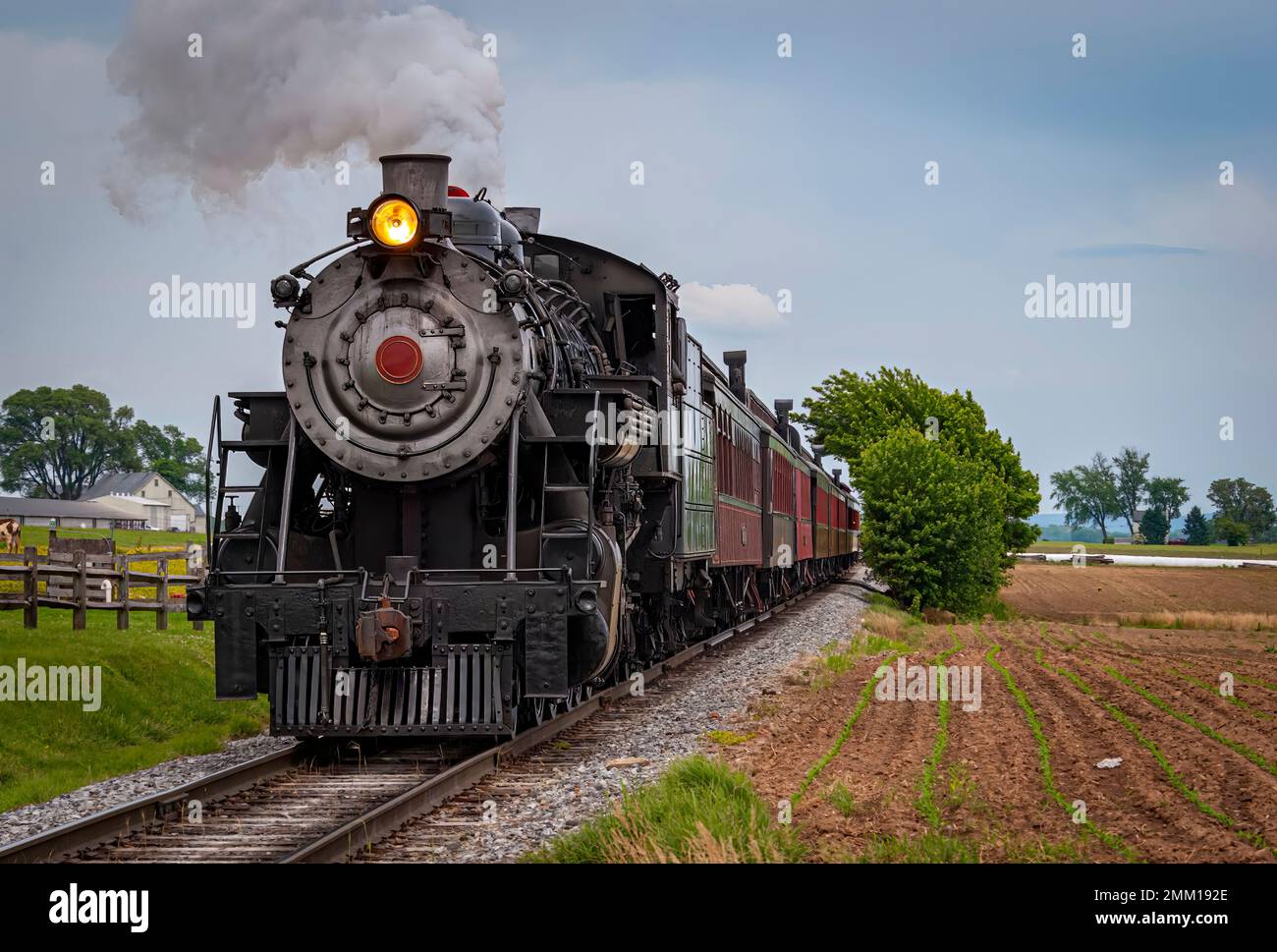 Vista di un treno a vapore restaurato che si avvicina a Head-on Blowing Smoke e Steam in un giorno di primavera Foto Stock