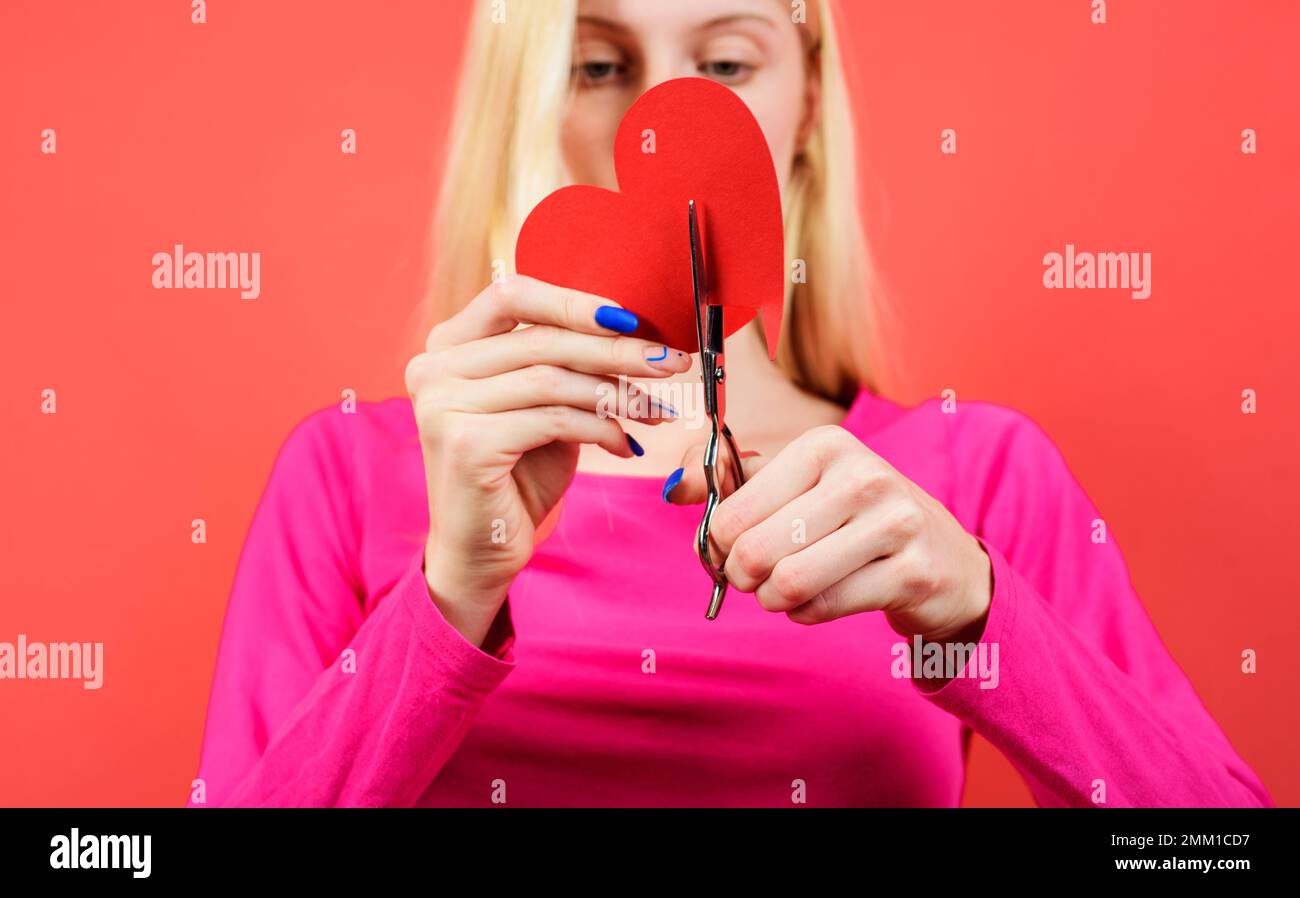 La ragazza taglia il cuore rosso con le forbici. Rompere relazioni, litigi e divorzio. Tradimento di otere. Foto Stock