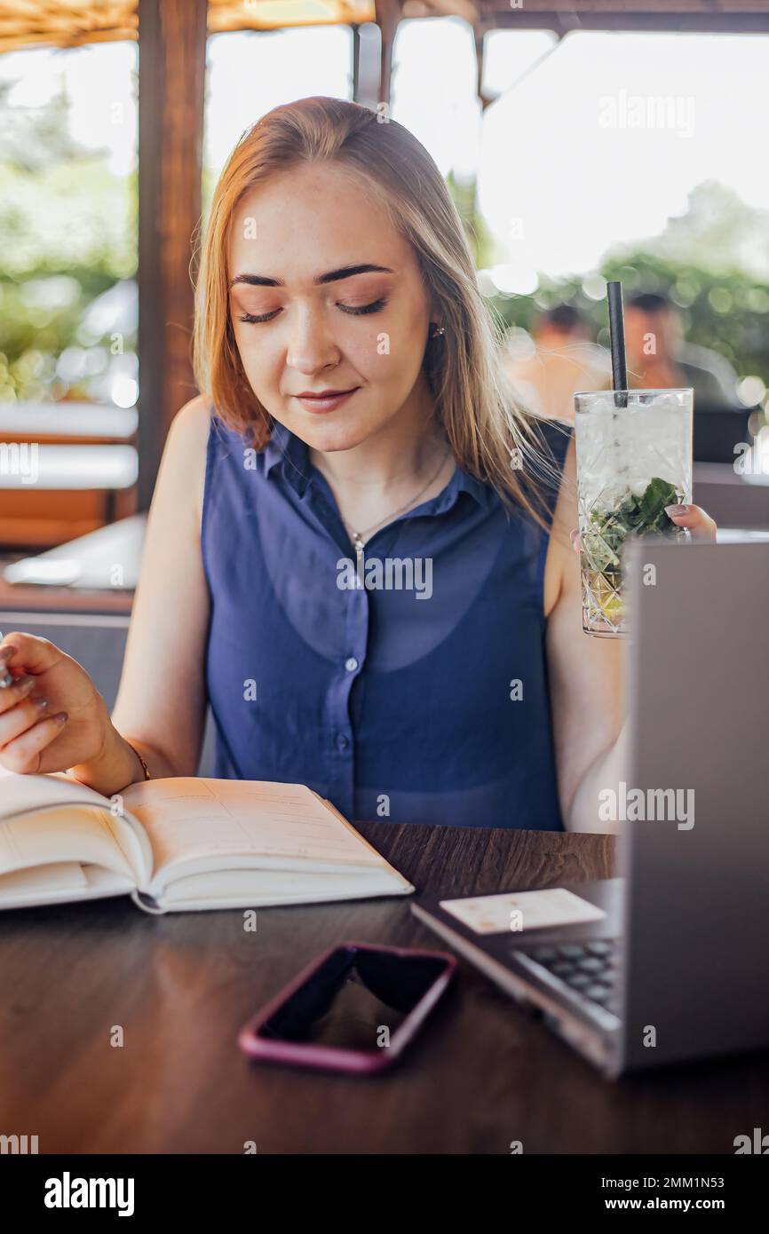 Bella donna con capelli corti seduta sulla terrazza una giornata di sole che lavora da casa utilizzando un computer portatile Foto Stock