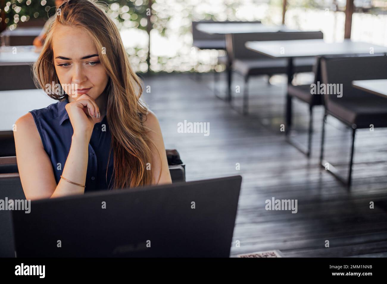 Giovane donna d'affari che lavora al computer in un bar. Una giovane ragazza downshifter lavora in un computer portatile, una giornata lavorativa. Foto Stock