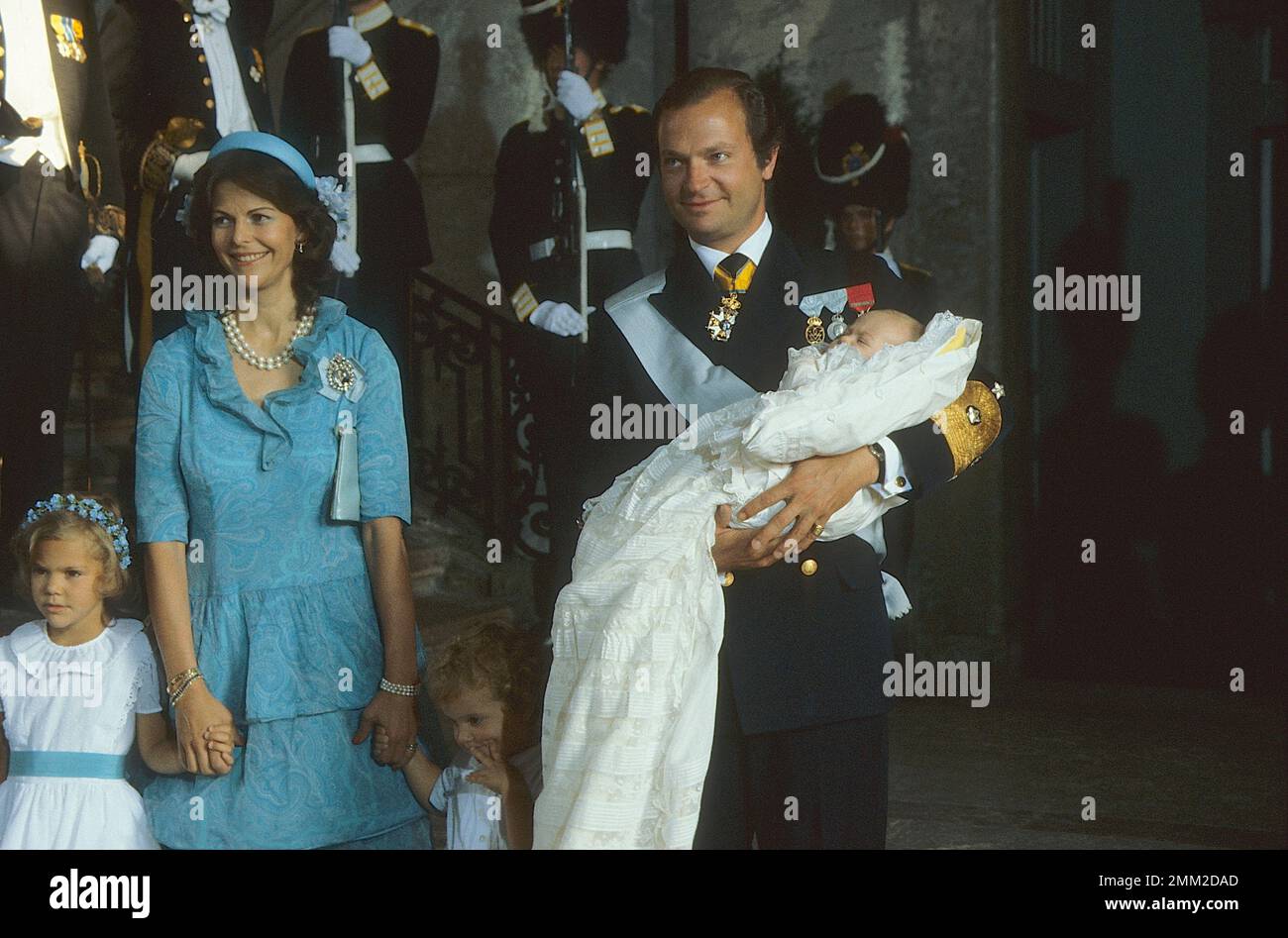 Carl XVI Gustaf, re di Svezia. Nato il 30 aprile 1946. Il re Carlo XVI Gustaf tiene la principessa Madeleine durante il battesimo di lei a Slottskyrkan Stoccolma 31 agosto 1982. La principessa della corona Victoria, la regina Silvia e il principe Carl Philip. Foto Stock