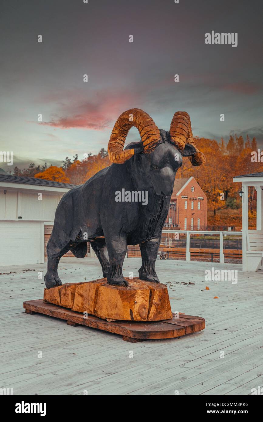Statua di capra nera fuori sul portico del ristorante con corna dorate in piedi alto e forte che domina lontano e oltre come un protettore. Foto Stock