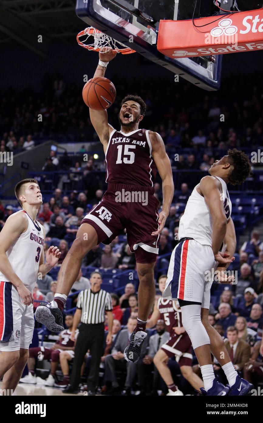 Texas A&M forward Isiah Jasey (15) dunks between Gonzaga forward Filip Petrusev (3) and forward Jeremy Jones during the second half of an NCAA college basketball game in Spokane, Wash., Thursday, Nov. 15, 2018. (AP Photo/Young Kwak) Foto Stock