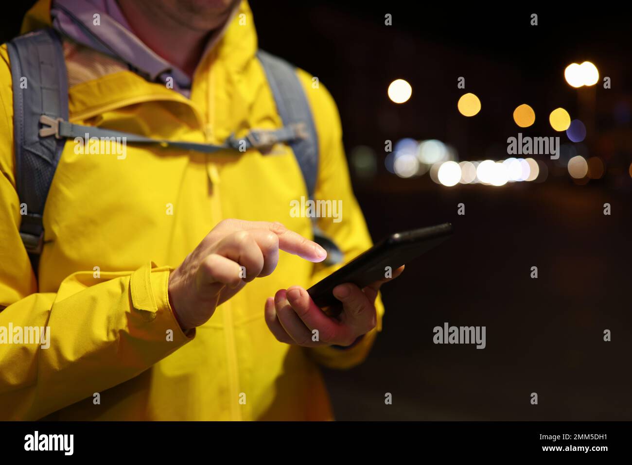 Uomo con zaino che usa il telefono cellulare sulla strada serale della città. Foto Stock