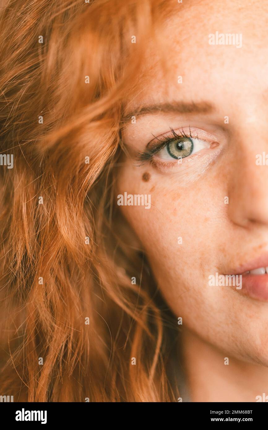 Chiusura di donna con capelli rossi e occhi verdi con un segno di bellezza Foto Stock