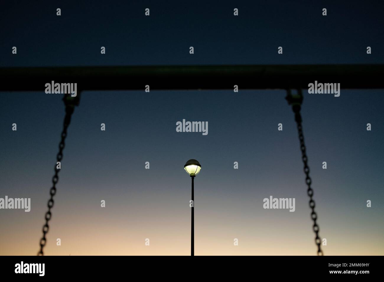 Fai oscillare la catena contro la luce che illumina il parco giochi Foto Stock