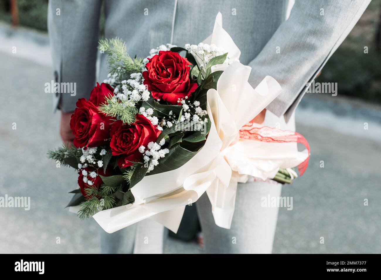 Primo piano di un uomo con bouquet di rose dietro la schiena. San Valentino Foto Stock