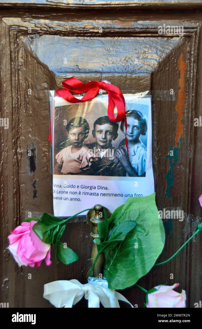 Nel giorno 2023 della memoria dell'Olocausto, una mano anonima ha fissato la foto di tre bambini e di alcuni fiori sulla porta vecchia al numero 5999 di Cannaregio, a Venezia. I bambini furono deportati ad Auschwitz, con i loro genitori e un fratello di un anno, nel 1943. Avevano 14, 10, 7 anni. Furono uccisi ad Auschwitz il 26 febbraio 1944 con il loro fratello di un anno. Alcuni anni fa, 7 "pietre di tumbling" sono state messe all'ingresso della loro casa. Una nota sotto la foto dice: "Anna, Guido e Giorgia Dina. Leone aveva un anno e non sapremo mai quale faccia aveva". Foto Stock