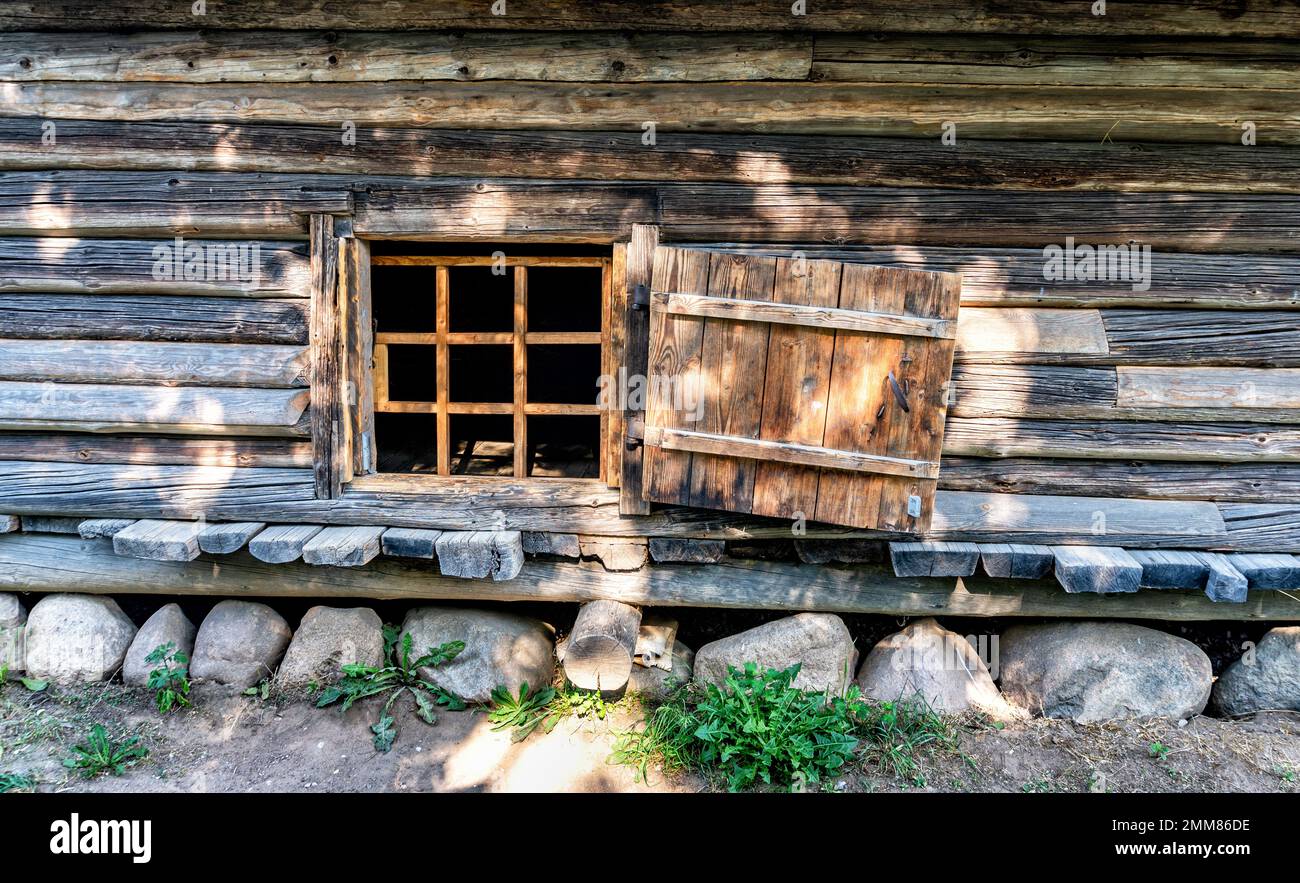 Piccola finestra nella parete di vecchia casa di legno di tronchi. Casa in legno vintage con piccola finestra Foto Stock