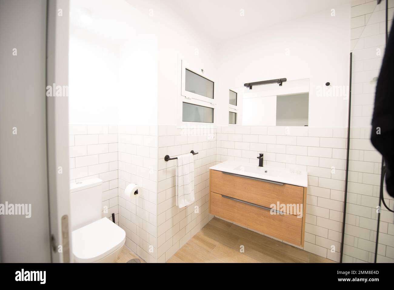 bagno moderno in una casa in tonalità bianche con legno Foto Stock