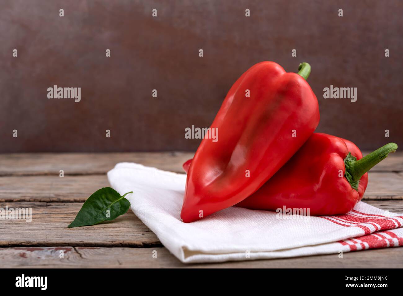 Peperoni rossi dolci e foglia verde su tavola di legno. Messa a fuoco selettiva. Foto Stock