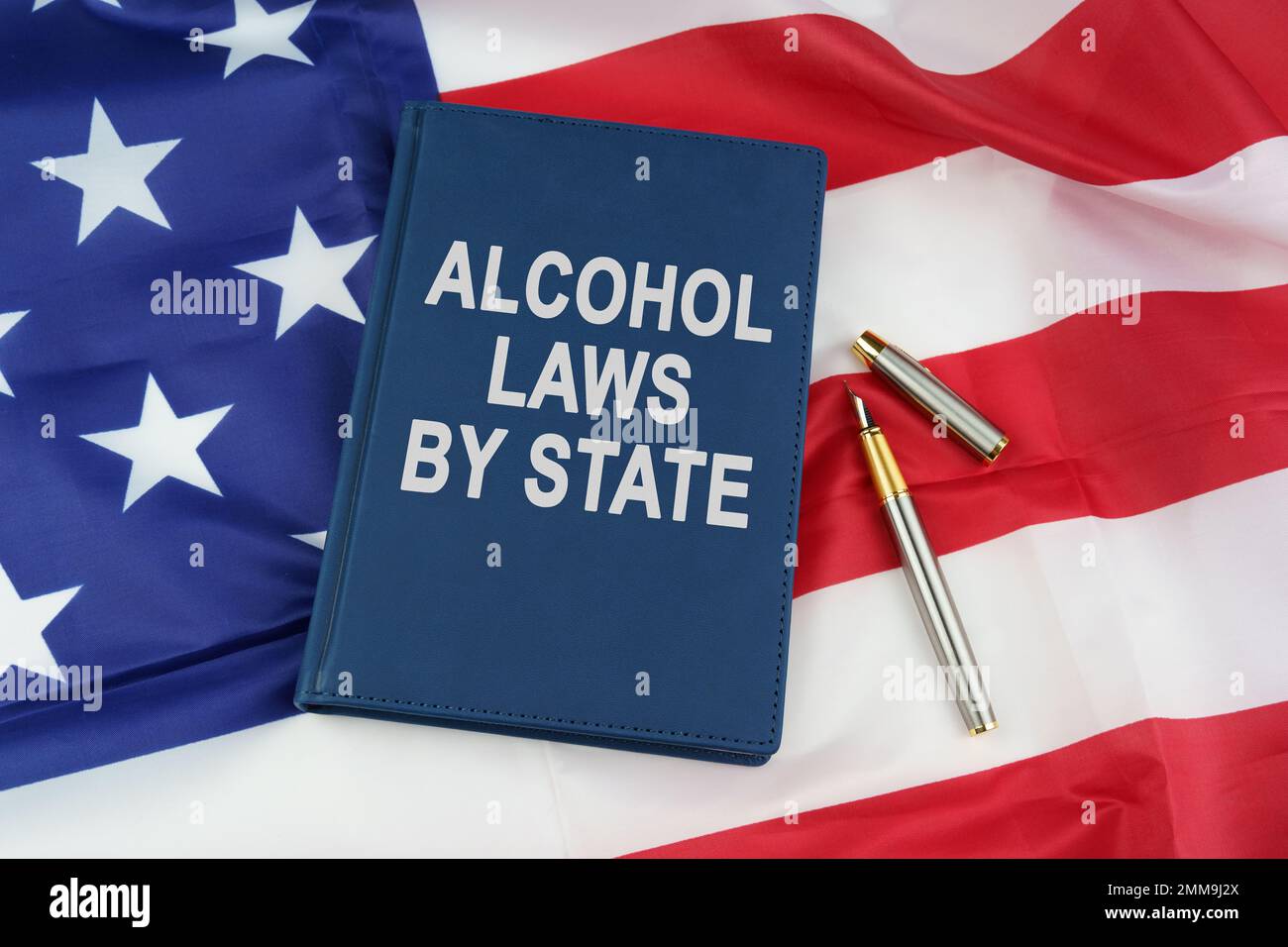 Concetto di legge. Sulla bandiera degli Stati Uniti si trova una penna e un libro con l'iscrizione - ALCOL LEGGI PER STATO Foto Stock