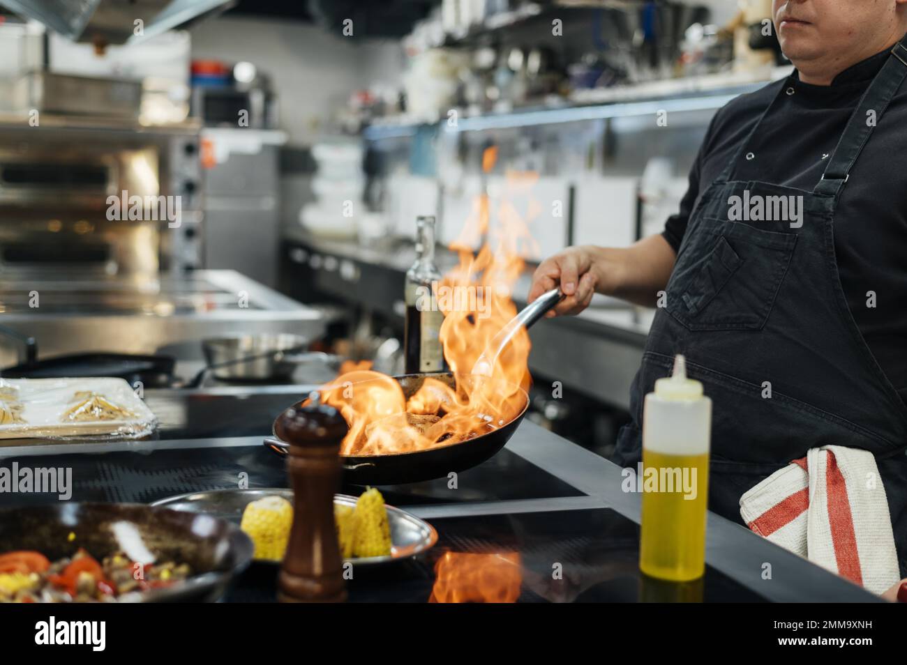 vista laterale piatto di flambing dello chef maschile. Risoluzione e foto di alta qualità Foto Stock