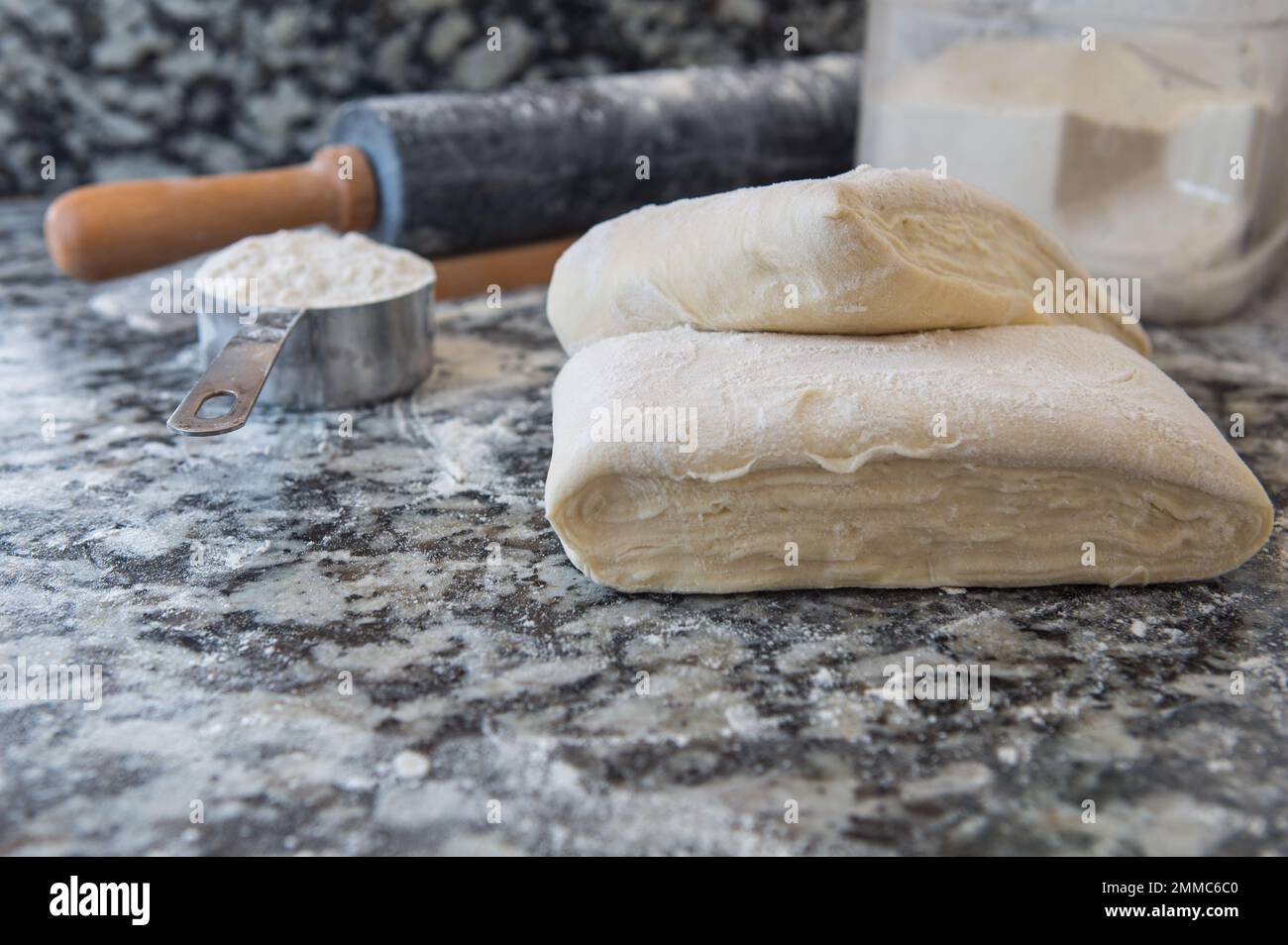 Pasta sfoglia fatta in casa con farina e un matterello sul piano della cucina in marmo Foto Stock