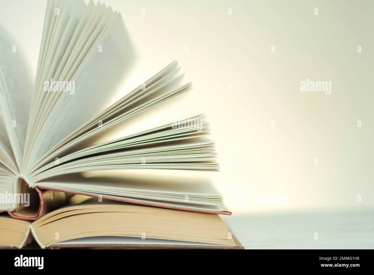 Lettura ed educazione. Apri i libri su uno sfondo chiaro con un gradiente giallo.pila di libri su un tavolo di legno.apprendimento e simbolo della conoscenza Foto Stock