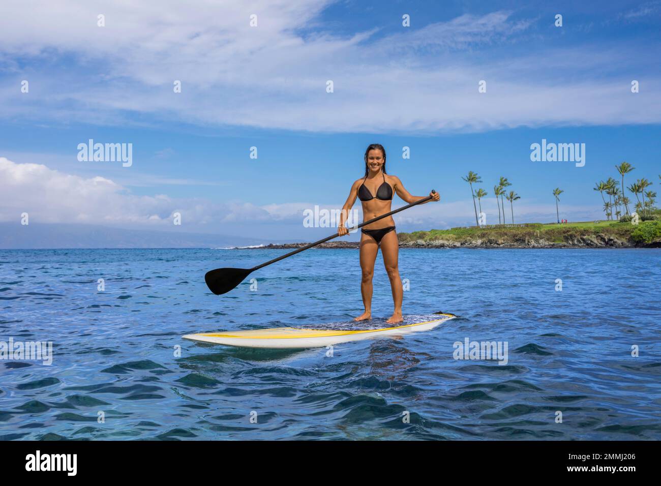 Ragazza (MR) in bikini su tavola di paddle stand-up a Kapalua Bay, Maui, Hawaii. Foto Stock