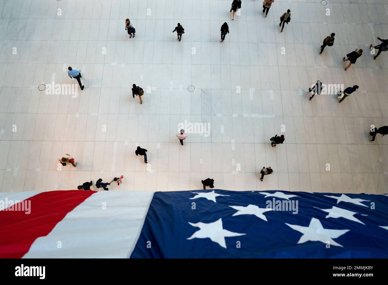 People walk under an American flag inside the Oculus, part of the World Trade Center transportation hub, on the anniversary of 9/11 terrorist attacks in New York on Tuesday, Sept. 11, 2018. (AP Photo/Craig Ruttle) Foto Stock
