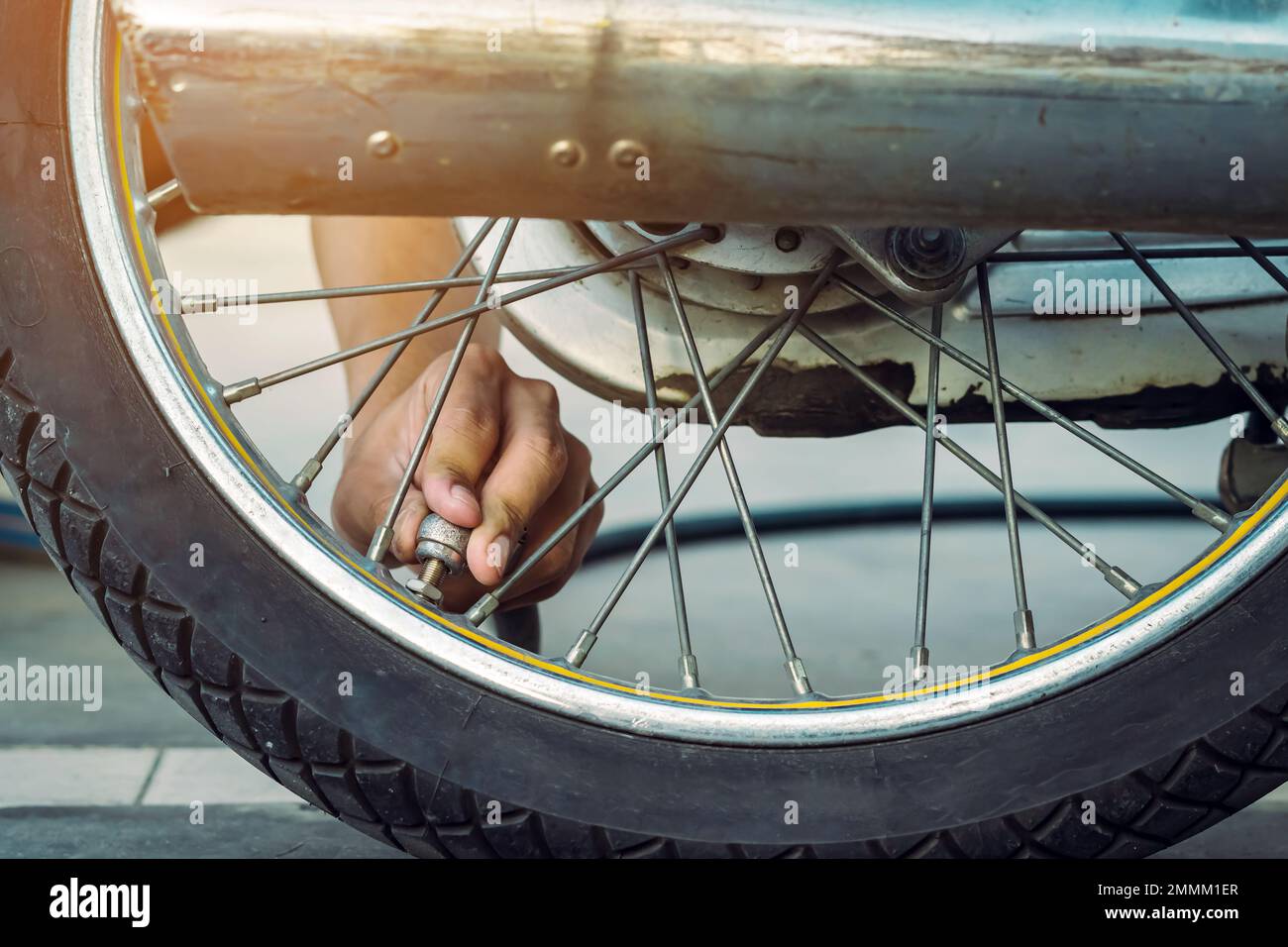 Mani di un uomo controllare la pressione del generatore di gas e gonfiare uno pneumatico su una motocicletta con un compressore pneumatico. Man controllo della pressione dell'aria e riempimento della pressione dei pneumatici Foto Stock