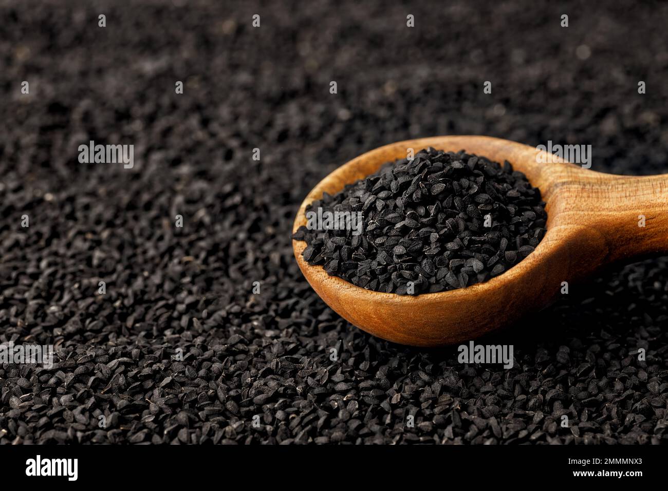 semi di cumino nero in paletta e sparsi sullo sfondo Foto Stock