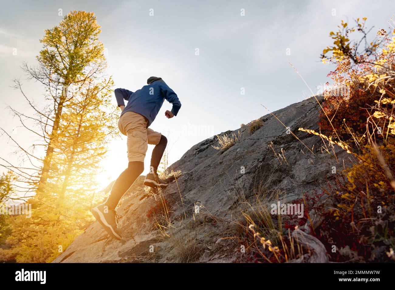 Runner man corre in salita traversata nella foresta al tramonto e le montagne Foto Stock