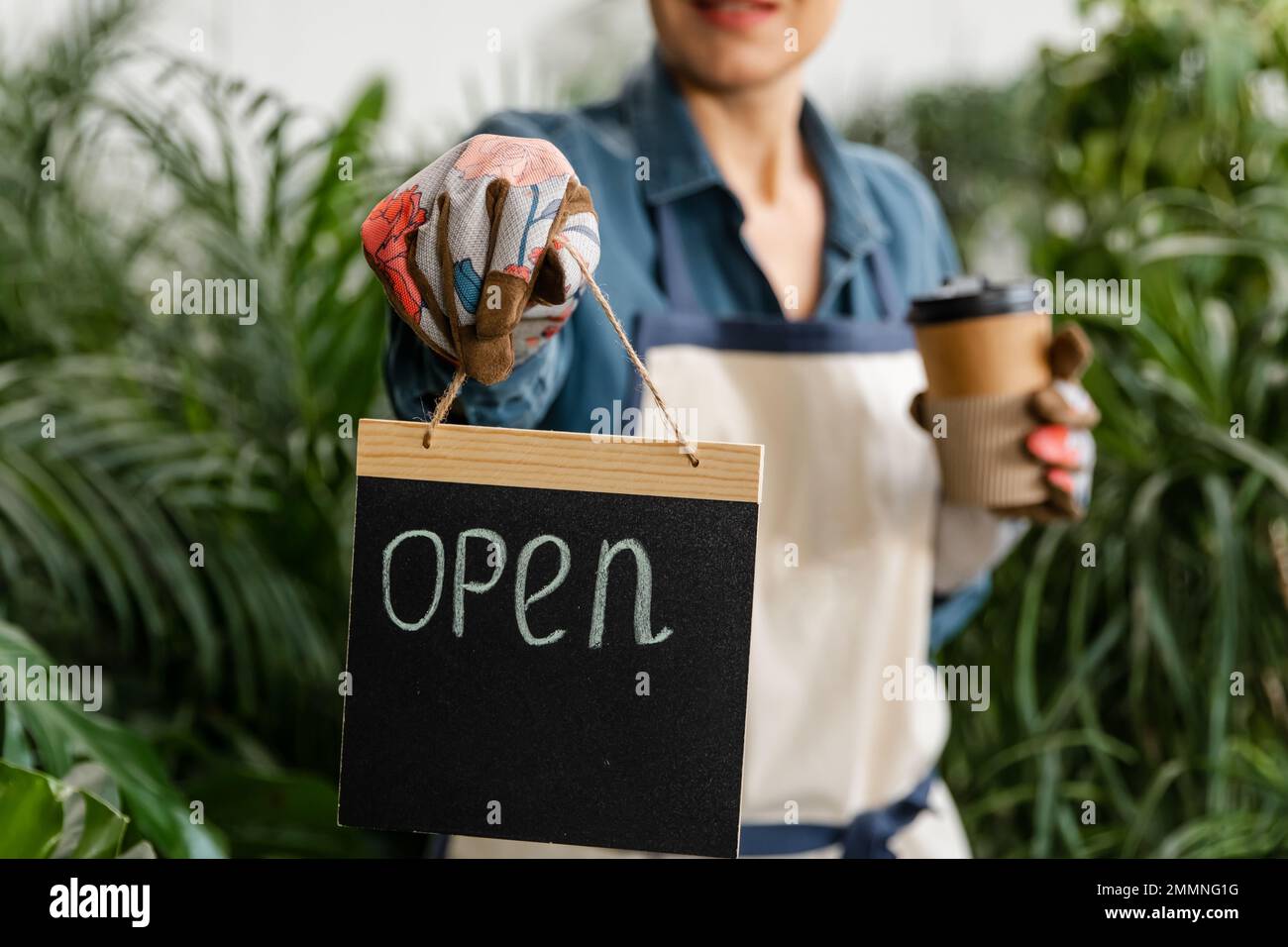 Imprenditore femmina in possesso di aprire segno in mani in negozio floreale. Foto Stock