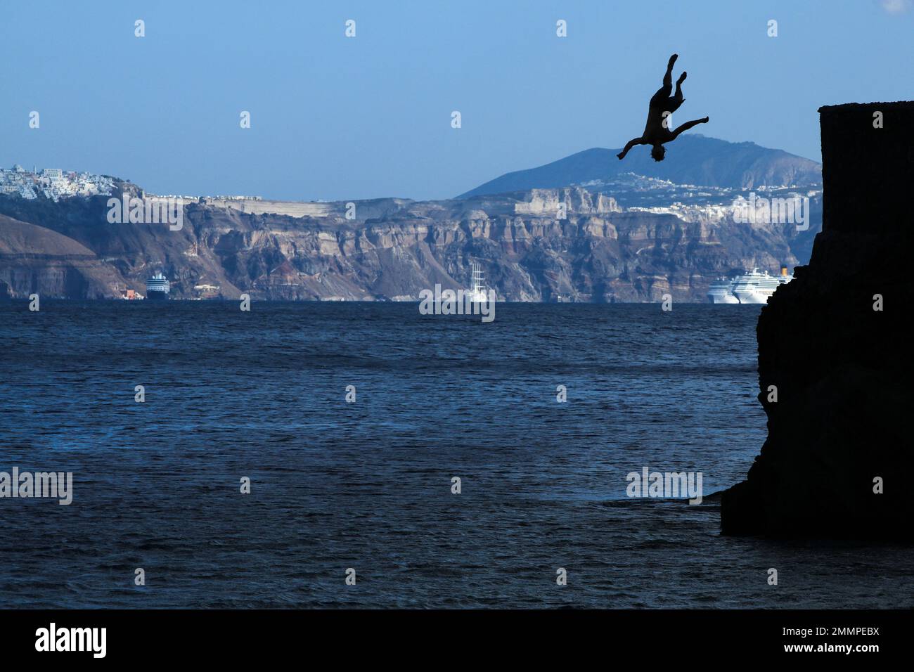 Un uomo si ribalta da una scogliera sull'isola di Santorini - Grecia Foto Stock