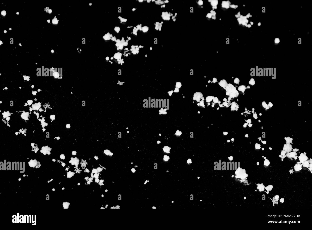 Molti fiocchi di neve su uno sfondo nero, l'immagine di sfondo assomiglia a un cielo stellato scuro. Foto Stock
