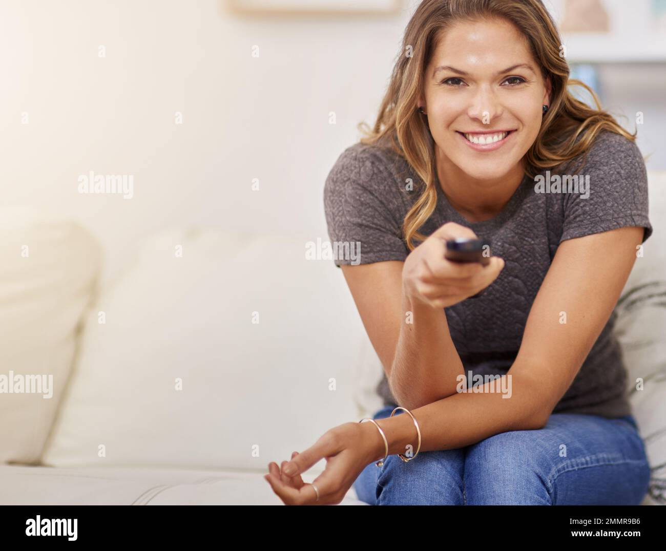 In controllo del suo intrattenimento di fine settimana. una giovane donna che trascorre un weekend rilassante a casa guardando la tv. Foto Stock