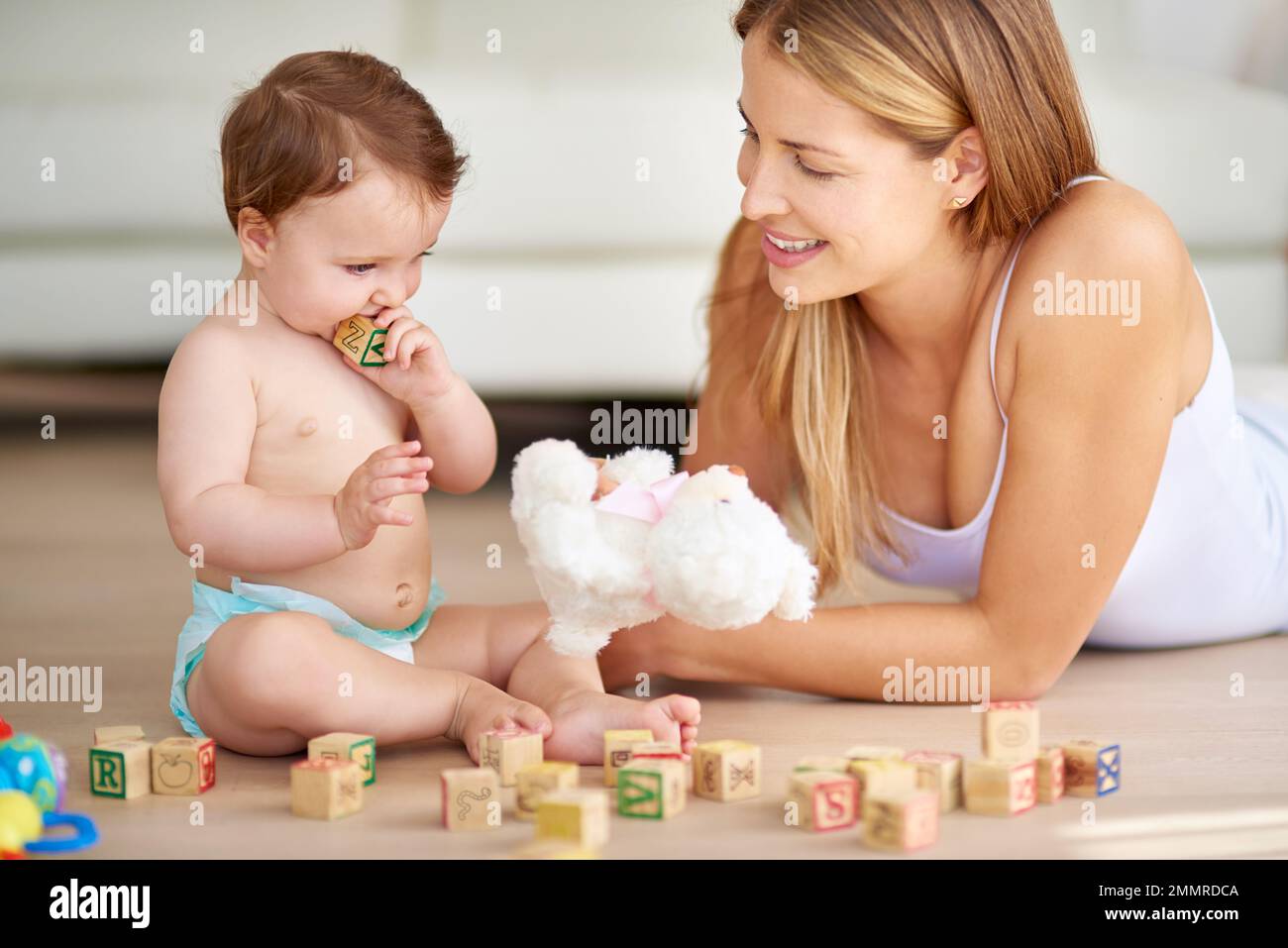 Sviluppare le sue capacità motorie e la coordinazione occhio-mano. una adorabile bambina e sua madre giocano a casa con blocchi di legno. Foto Stock