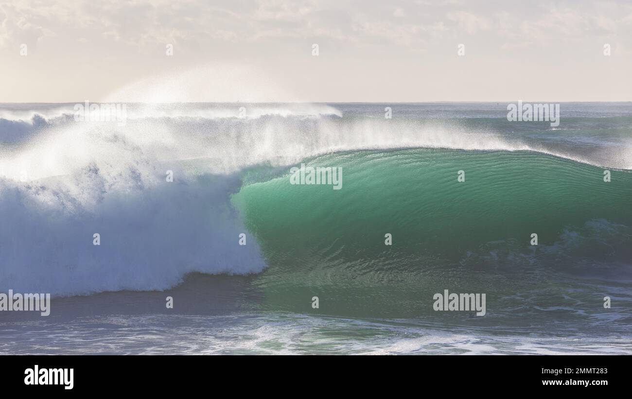 Onde oceaniche grande tropicale color smeraldo parete d'acqua che si infrange con spray retroilluminato. Foto Stock