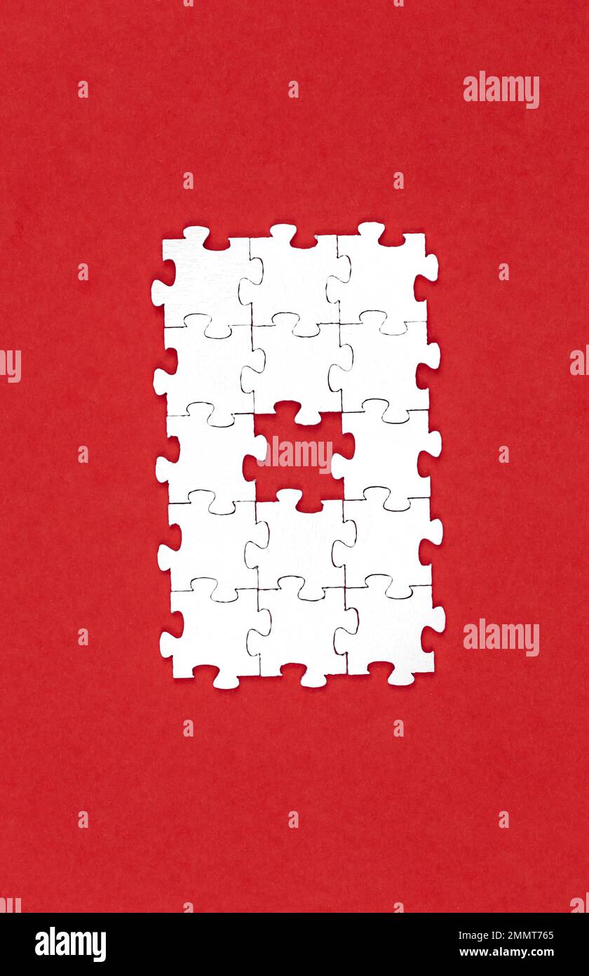 Puzzle bianchi su sfondo rosso, piatto. Foto Stock