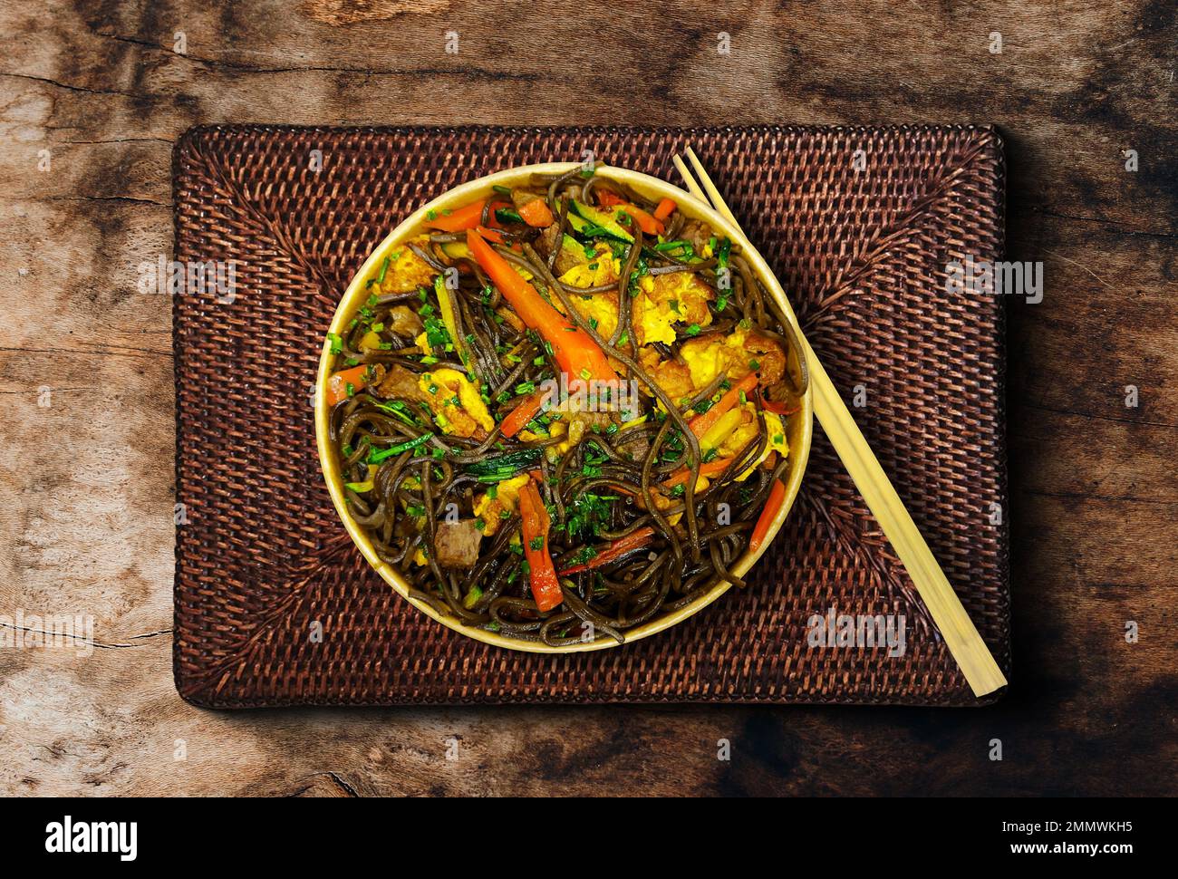 Vista dall'alto del manzo e delle verdure di Soba, tagliatelle di grano saraceno su un vecchio sfondo di tavoli di legno. Cucina asiatica tradizionale. Foto Stock